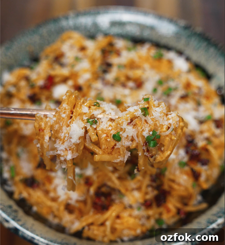 Chili Oil & Caramelized Onion Pasta Recipe for Flavorful Dinner 3 Close-up of a forkful of chili oil caramelized onion pasta topped with parmesan and scallions.