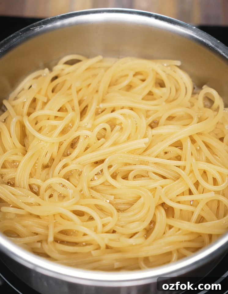 Chili Oil & Caramelized Onion Pasta Recipe for Flavorful Dinner 4 Spaghetti boiling in a stainless steel pot, cooked until al dente for the chili oil pasta.