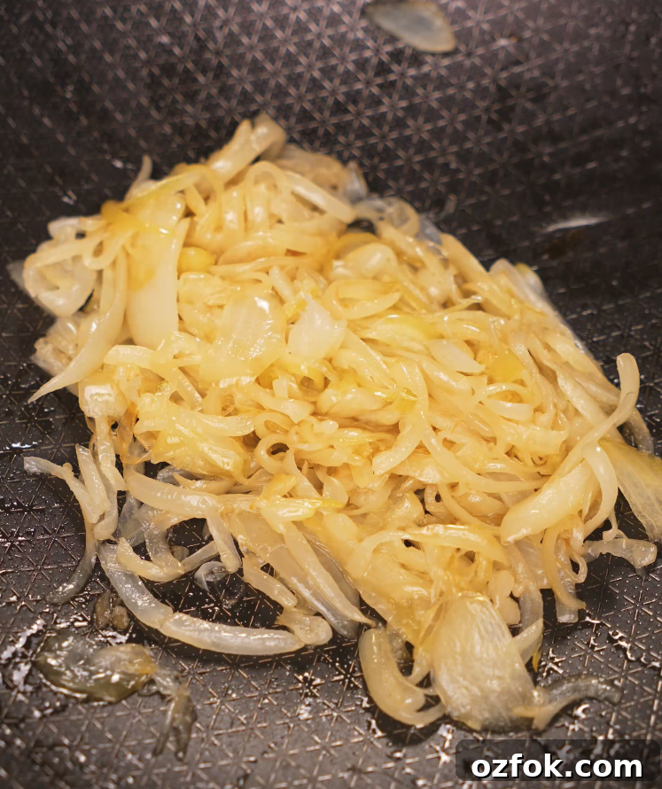 Chili Oil & Caramelized Onion Pasta Recipe for Flavorful Dinner 5 Thinly sliced onions caramelizing in oil in a nonstick pan for the base of the chili oil pasta.