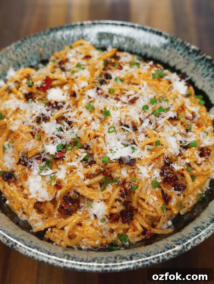 Chili Oil & Caramelized Onion Pasta Recipe for Flavorful Dinner 8 Final plated bowl of creamy chili oil caramelized onion pasta topped with grated parmesan, chili crisp, and chopped scallions.