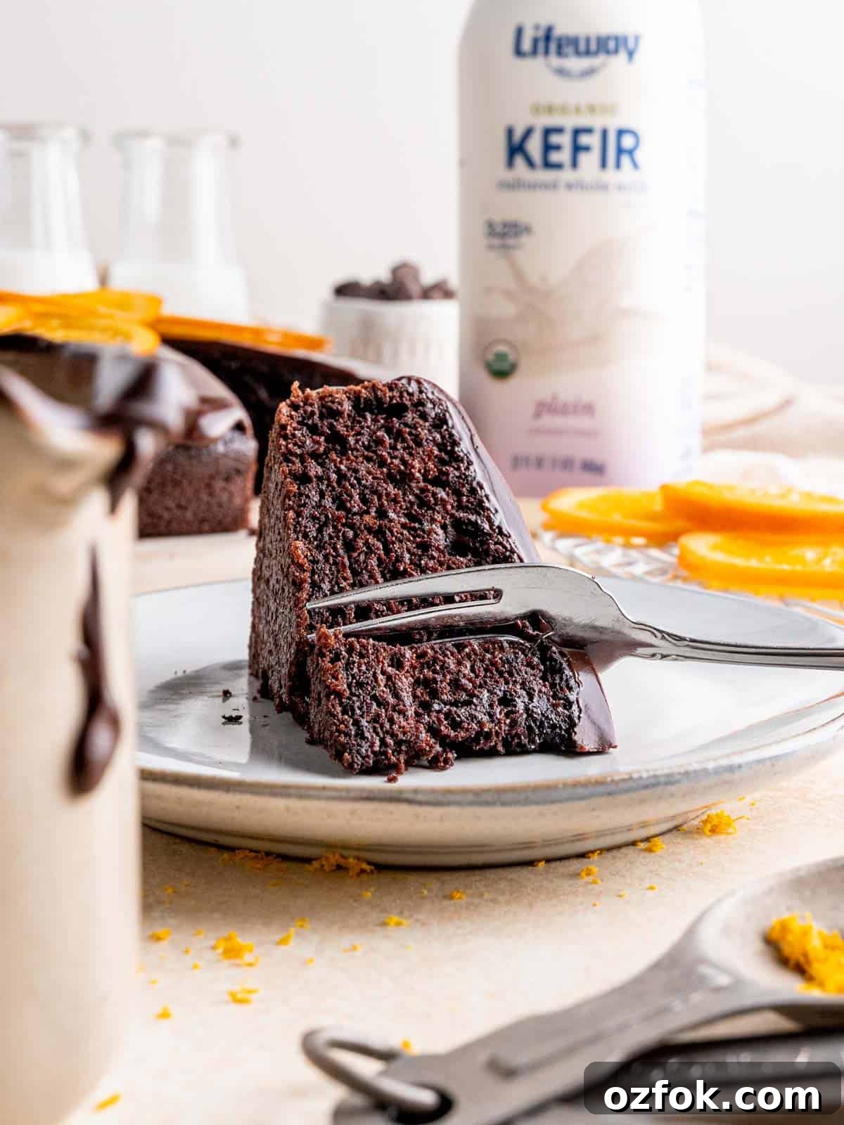 A fork cutting into a slice of cake with a bottle of Lifeway Kefir in the background.