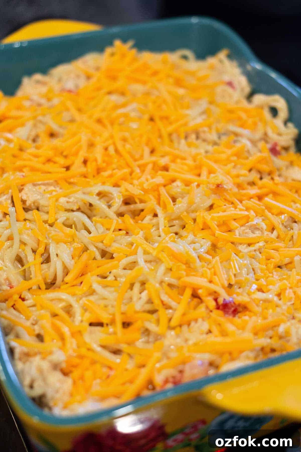 Creamy Rotel Chicken Spaghetti with Velveeta Cheese 7 Chicken spaghetti in a 9 by 13 baking dish topped with shredded cheddar.