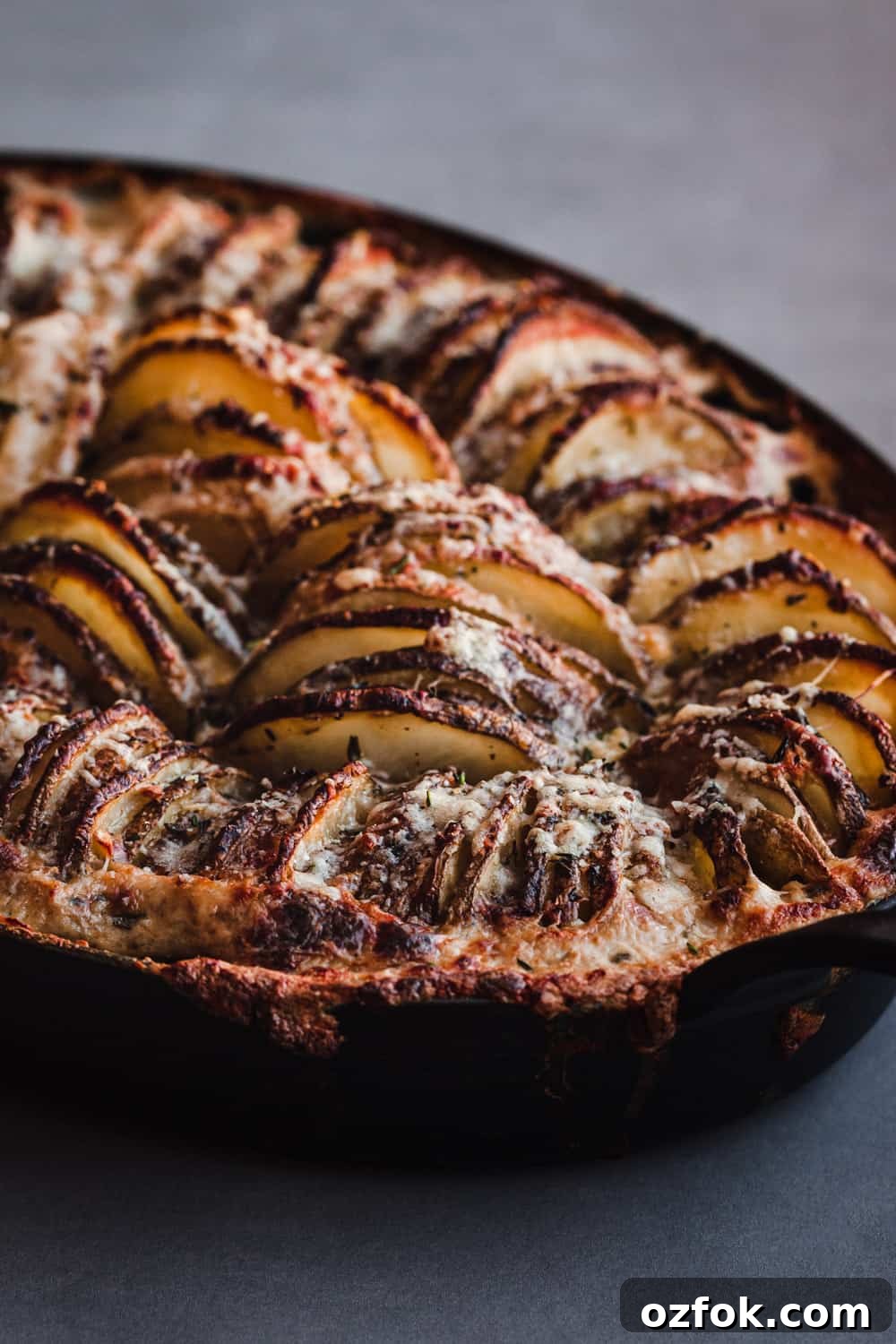 Crispy Hasselback Potato Gratin: Creamy Layered Comfort Dish 8 hasselback potato gratin, in a cast iron oven dish, 45 degree angle shot.