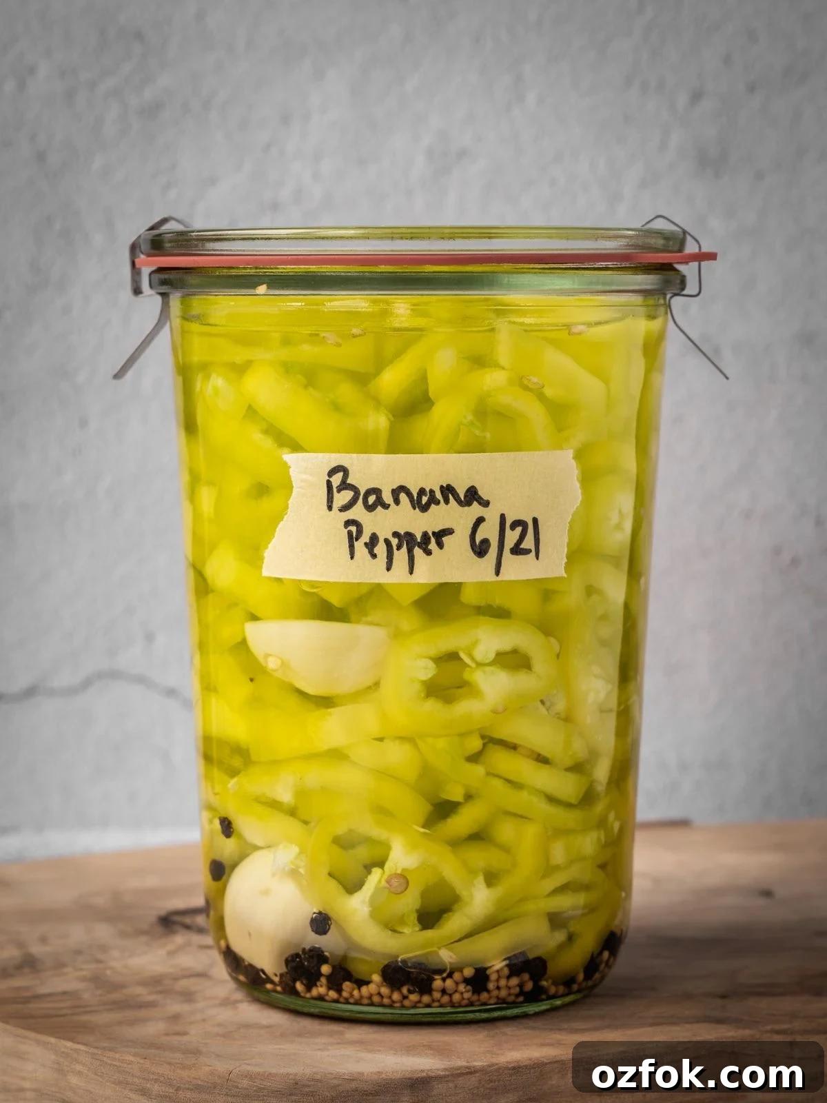 Sealed and labeled mason jar full of sliced banana peppers, garlic and spices.