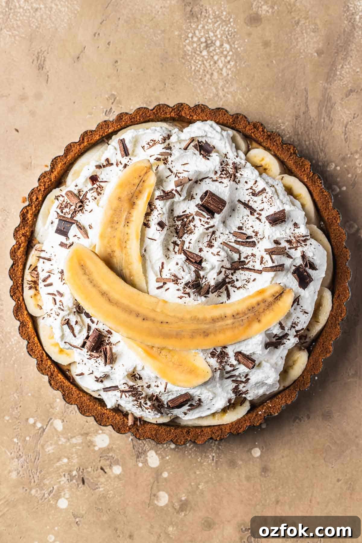 Banoffee Tart Recipe: Caramelized Banana Tart with Buttery Crust 11 Banoffee tart with whipped cream, chocolate shavings and a banana sliced lengthways.