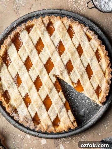A lattice topped crostata di marmellata with one slice removed.