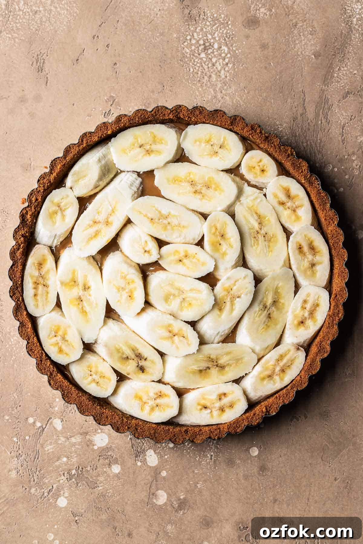 Banoffee Tart Recipe: Caramelized Banana Tart with Buttery Crust 7 Sliced bananas on top of dulce de leche in a biscoff tart crust.
