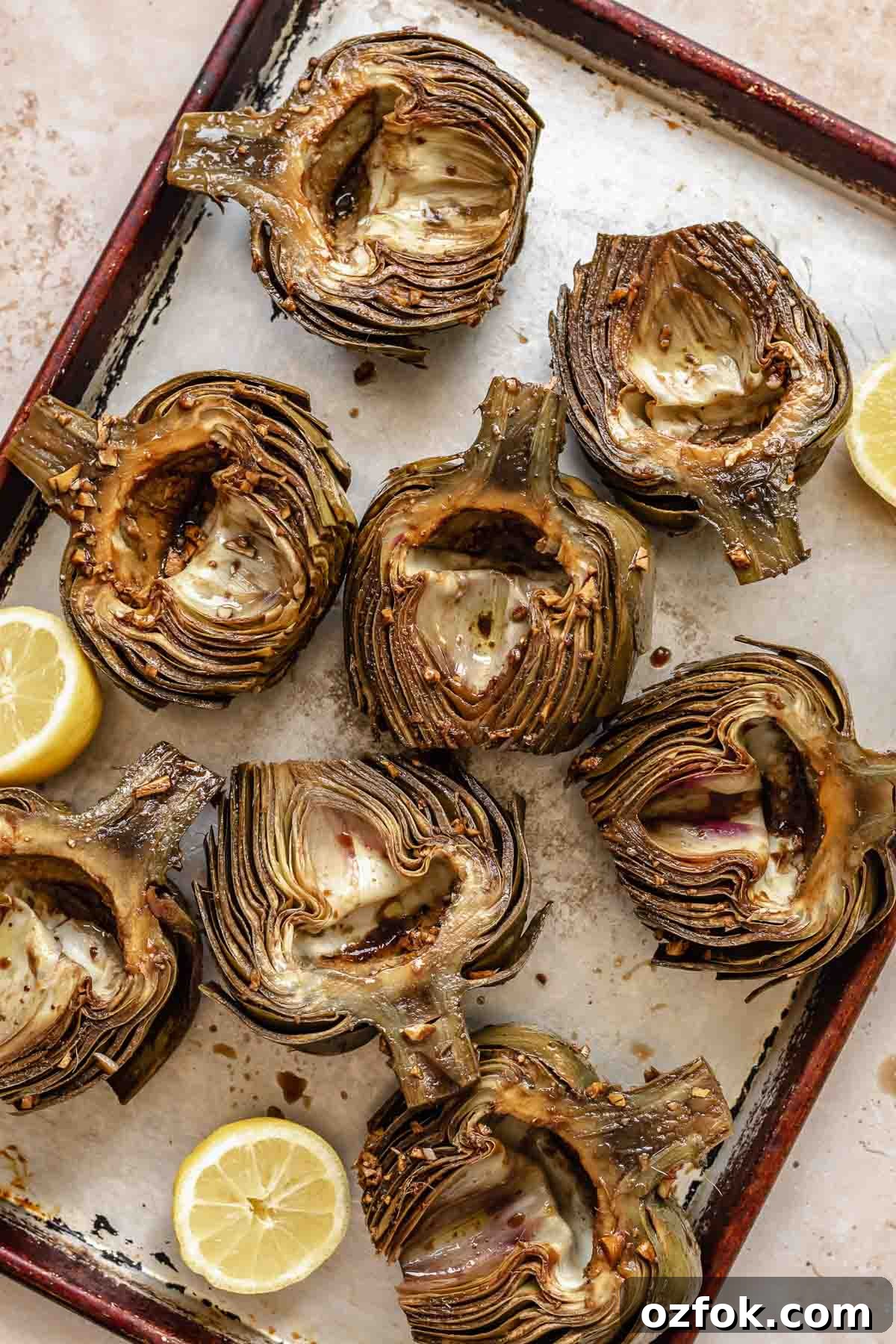Grilled Marinated Artichokes with Lemon Aioli Recipe 13 Marinated artichoke halves on a cookie sheet.