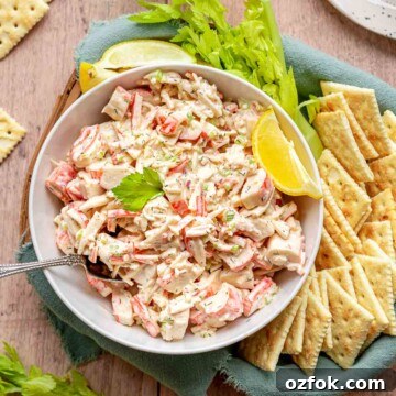 Imitation crab salad in a bowl with crackers, celery, and lemon.