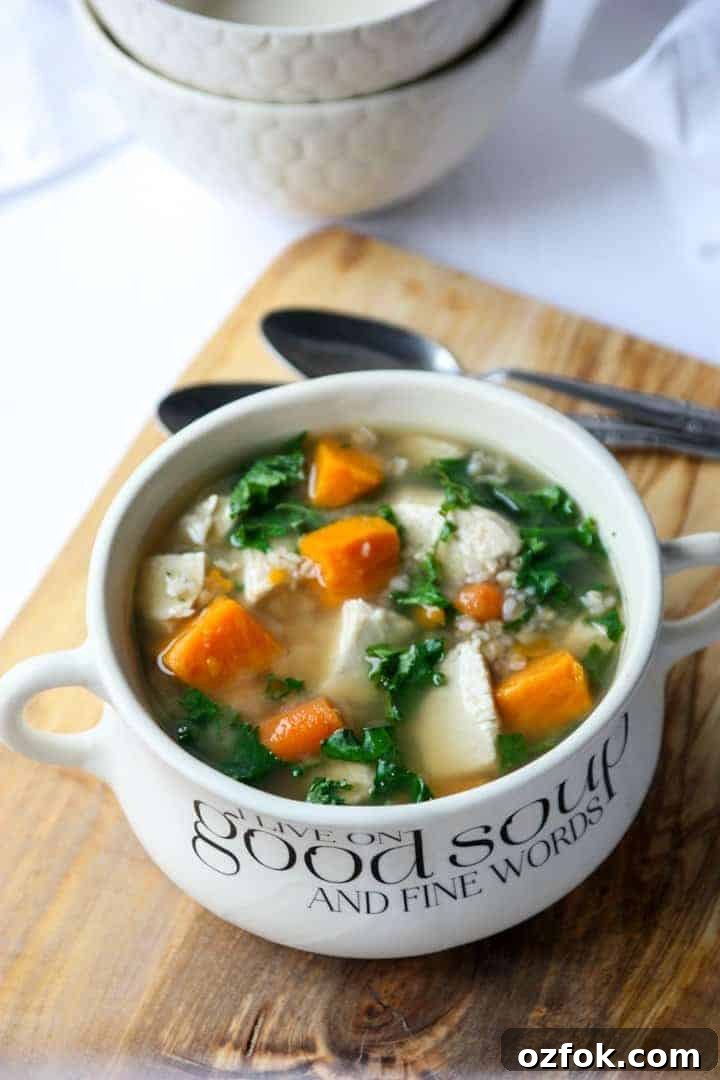 Turkey, Sweet Potato & Kale Buckwheat Soup Recipe 2 Buckwheat Soup with turkey, sweet potatoes and kale in a white bowl on a wood cutting board.