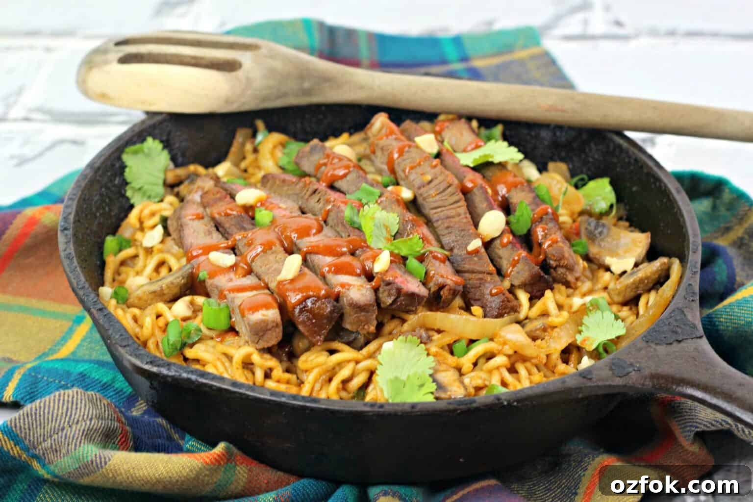 Spicy Korean Noodles Recipe — Authentic Bibim Guksu Guide 6 A dish of the completed steak dish with fresh herbs on top.