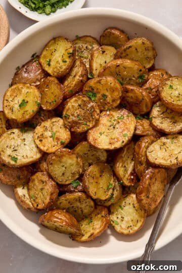 Air fryer baby potatoes served in a white bowl and topped with sea salt and chopped fresh parsley.