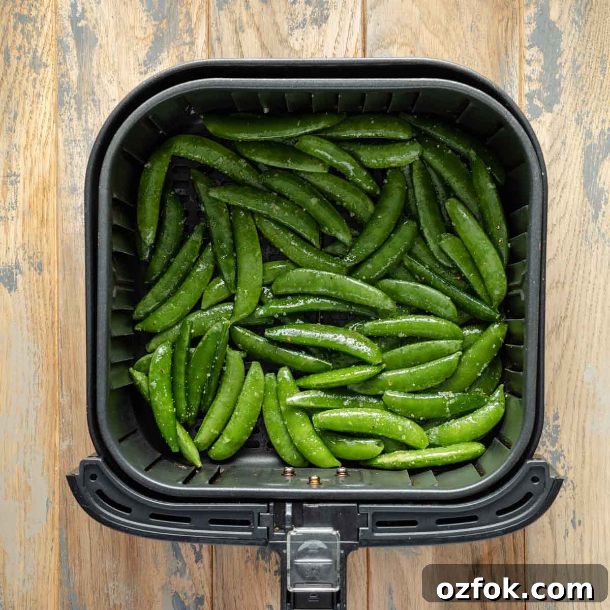 Crispy Air-Fried Snap Peas Recipe (15-Minute Side) 5 Raw and seasoned snap peas in air fryer basket.