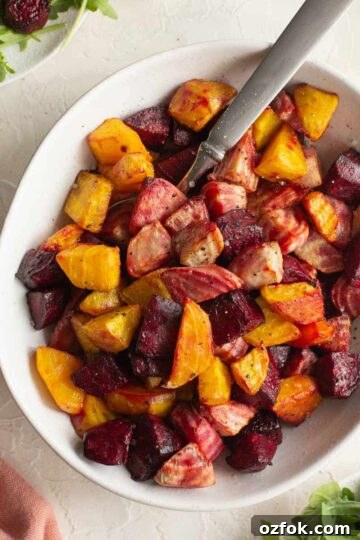 Chopped beets (red, golden and candy cane) air fried and served in a white bowl with a spoon.