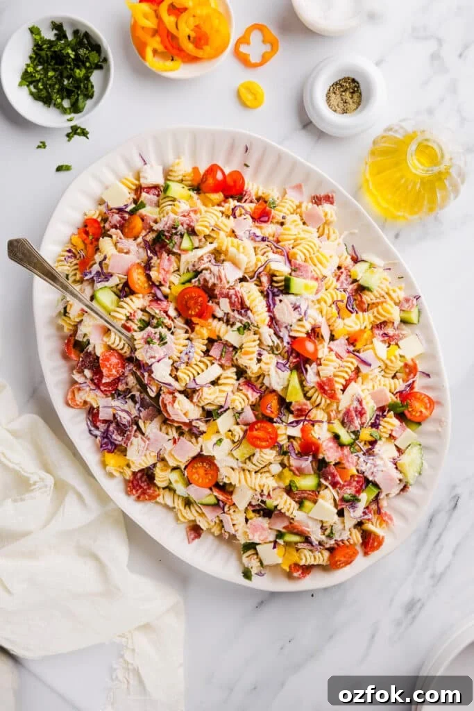 Grinder Pasta Salad Recipe with Italian Meats and Cheese 2 Grinder pasta salad on a large white platter with a serving spoons.