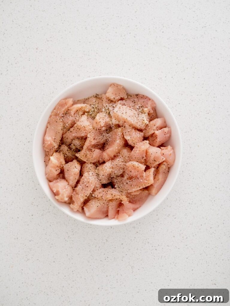 Classic Homemade General Tso's Chicken Recipe for Dinner 4 Seasoning sprinkled over raw chicken chunks in a bowl.