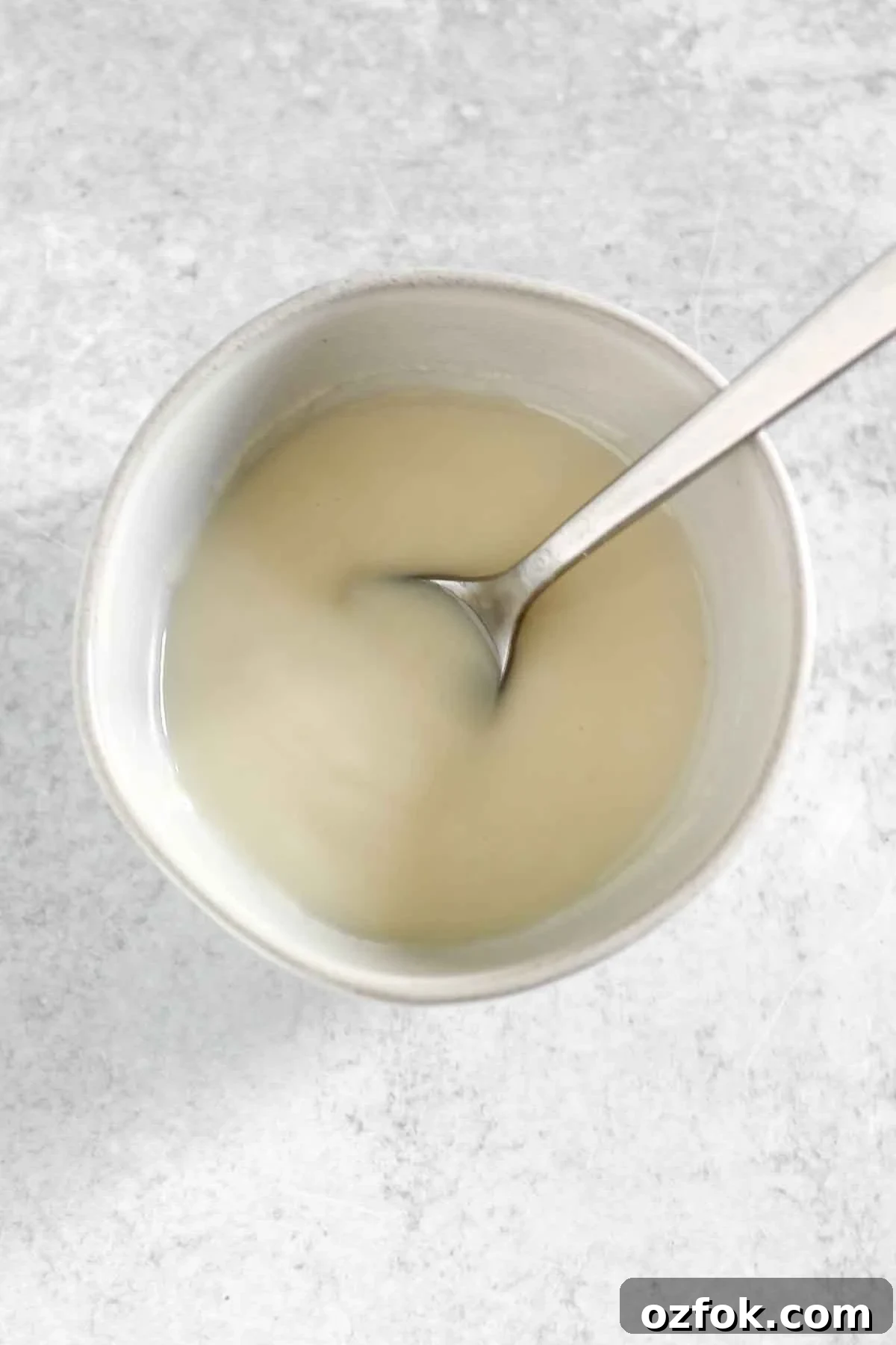 Paleo Coconut Butter Glaze Recipe for Cakes and Donuts 5 Melted coconut butter in a small bowl with a spoon.