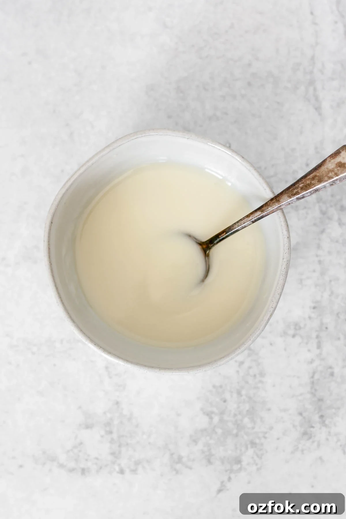 Paleo Coconut Butter Glaze Recipe for Cakes and Donuts 9 Coconut butter icing with a vintage spoon in a small ceramic bowl.