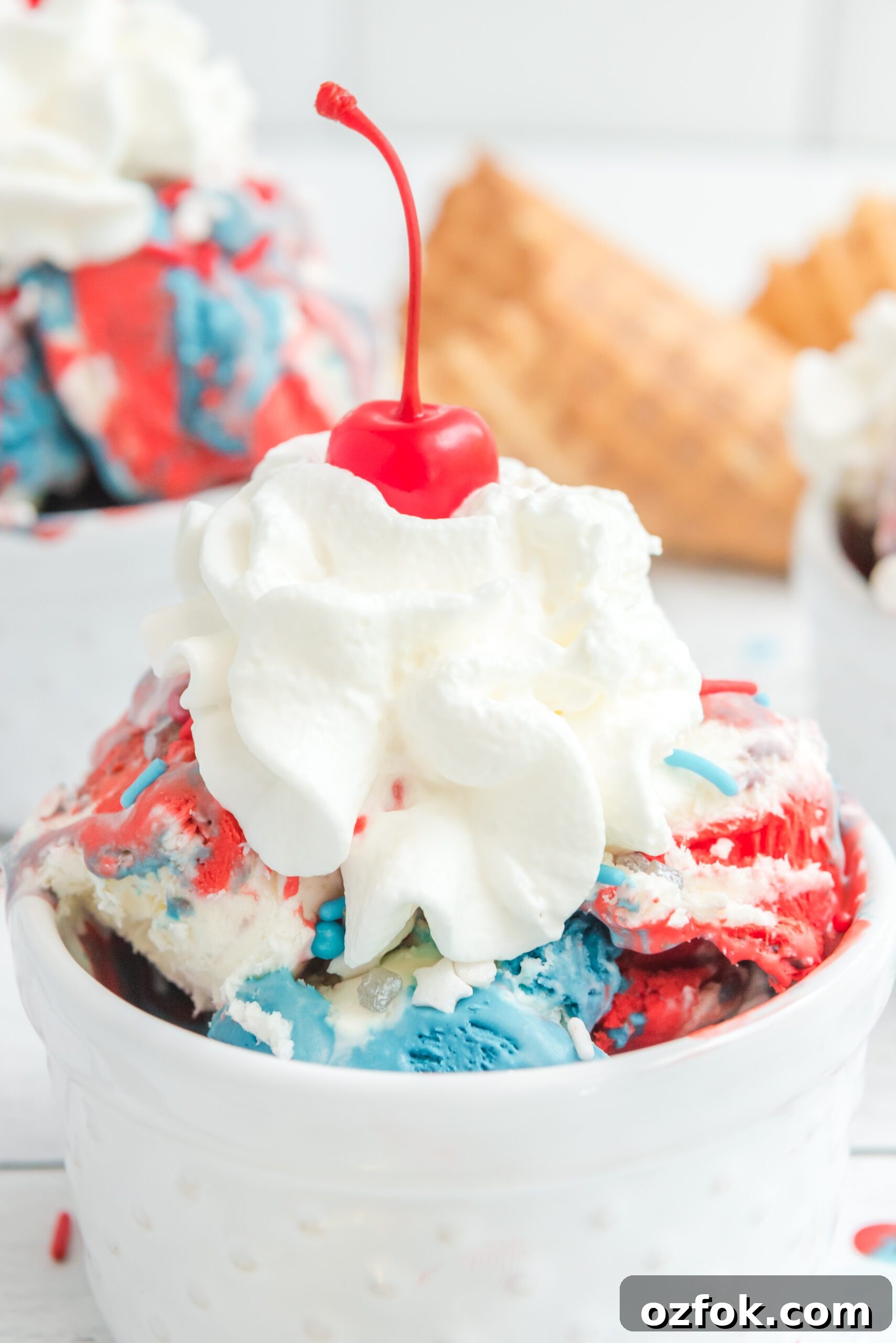 Patriotic Red, White & Blue Ice Cream Recipe for Summer Parties 8 Red, White & Blue Ice Cream in a white bowl topped with whipped cream and a cherry