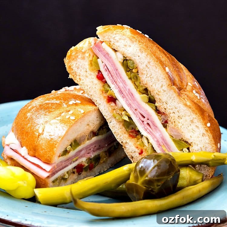 Close up of a NC muffuletta sandwich cut in half served with pickled vegetables.