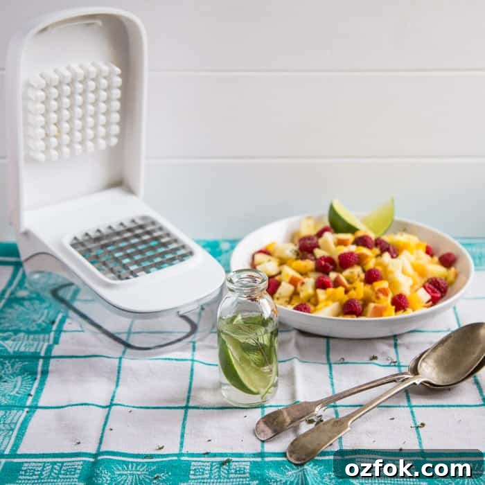 Mojito Fruit Salad Dressing Recipe: Fresh Lime & Mint Vinaigrette 4 Mojito Fruit Salad Dressing in a glass bottle beside the vegetable chopper and a bowl of fruit and 2 spoons on a green and white checked cloth