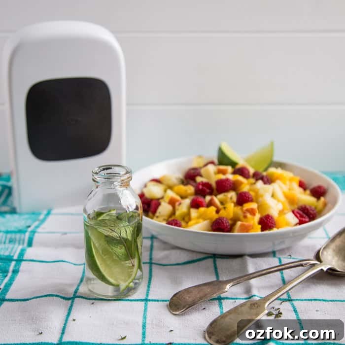 Mojito Fruit Salad Dressing Recipe: Fresh Lime & Mint Vinaigrette 5 Mojito Fruit Salad Dressing in a glass bottle beside the vegetable chopper and a bowl of fruit and 2 spoons on a green and white checked cloth