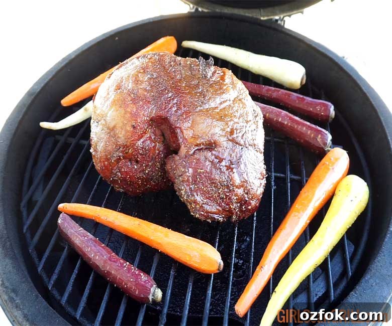 Grilled Australian Leg of Lamb Roast Recipe 6 uncooked lamb roast setting on a black grill grate with carrots