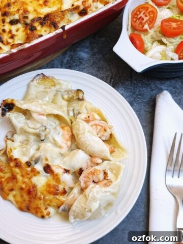A plate of seafood stuffed pasta shells covered in cheese sauce.