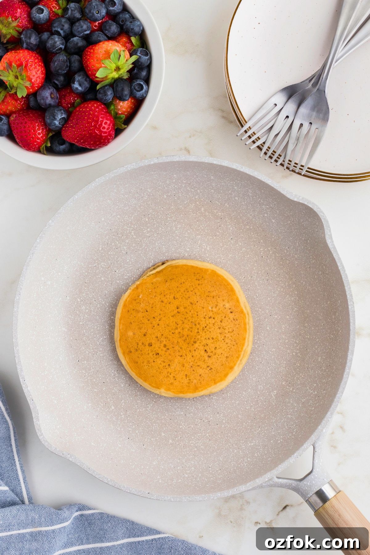 Golden fluffy pancake in the middle of the skillet after being cooked.