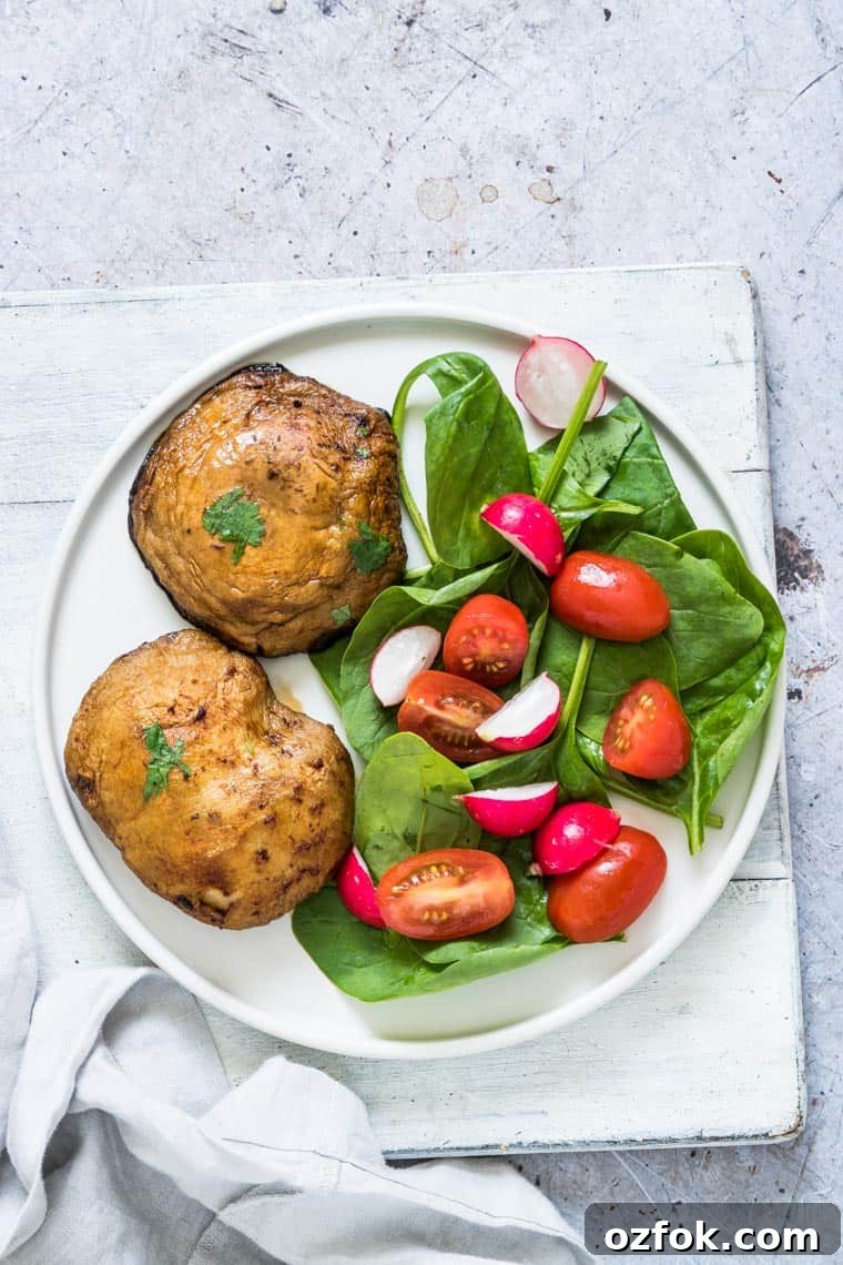 Garlic Mushroom Steak Recipe — Air Fryer & Grill (Vegan, Keto) 4 two portobello mushroom steaks on a white plate with a green salad