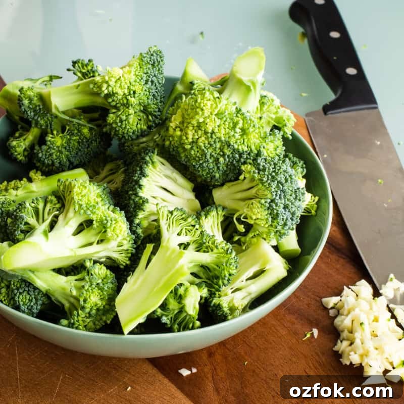 Garlic Broccoli Stir-Fry Recipe with Savory Sauce 4 Fresh broccoli florets in a bowl on a cutting board with minced garlic