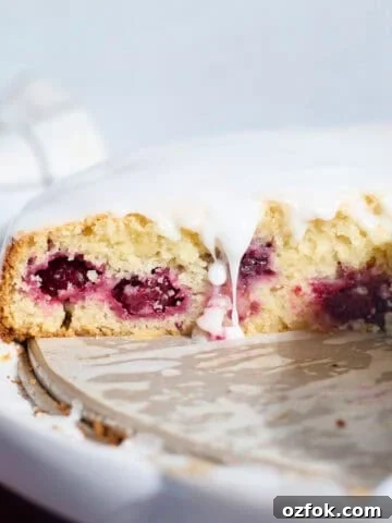 Sourdough Lemon Blackberry Cake with a drip of glaze falling down the side.