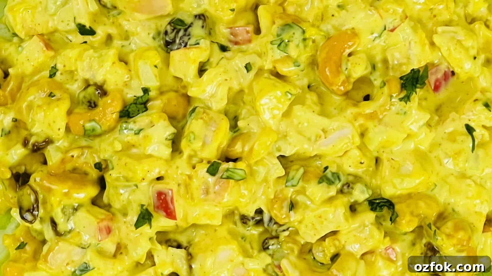 29 Irresistible Salad Recipes Everyone Will Love 13 Close-up of a dish featuring a creamy yellow curry with chunks of vegetables, cashews, and raisins, garnished with fresh herbs.