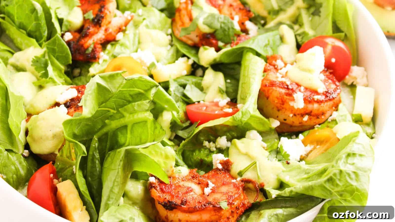 29 Irresistible Salad Recipes Everyone Will Love 17 A bowl of mixed salad with grilled shrimp, avocado, cherry tomatoes, lettuce, feta cheese, and a creamy dressing.