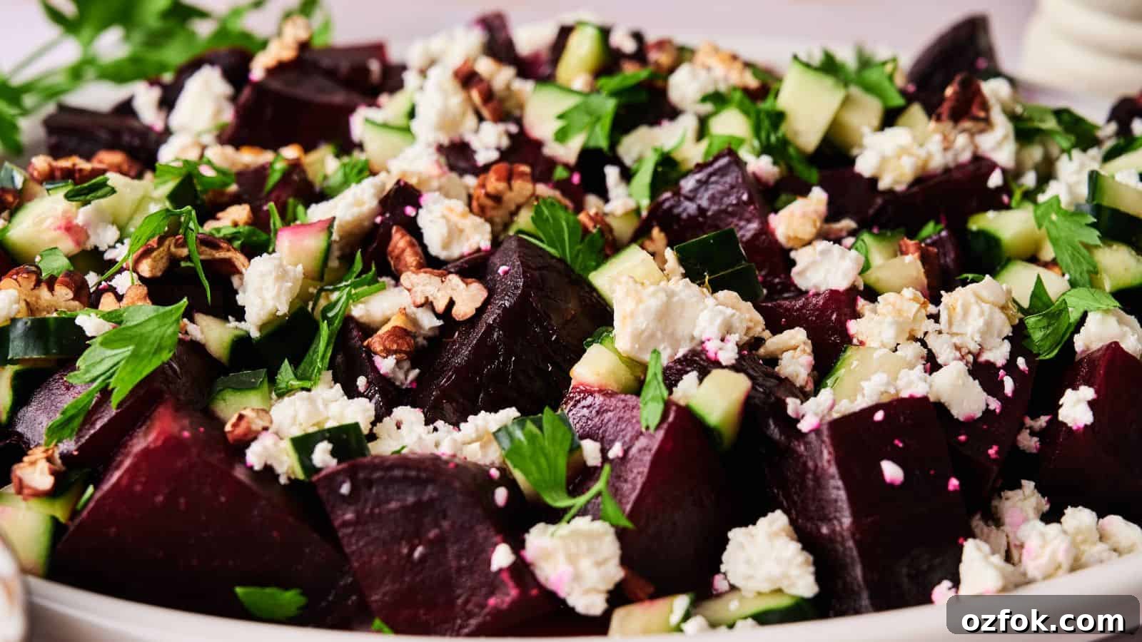 29 Irresistible Salad Recipes Everyone Will Love 3 A close-up of a salad featuring chopped beets, cucumber, feta cheese, walnuts, and fresh herbs on a white plate.