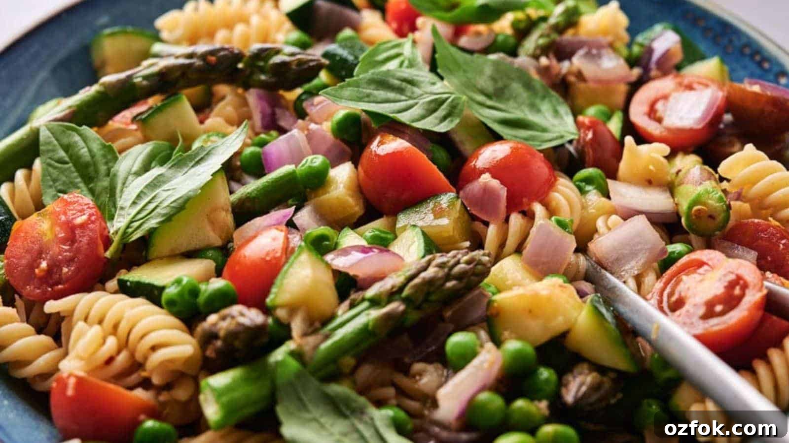 29 Irresistible Salad Recipes Everyone Will Love 21 A colorful Pasta Primavera salad with cherry tomatoes, asparagus, peas, and spinach in a blue bowl.