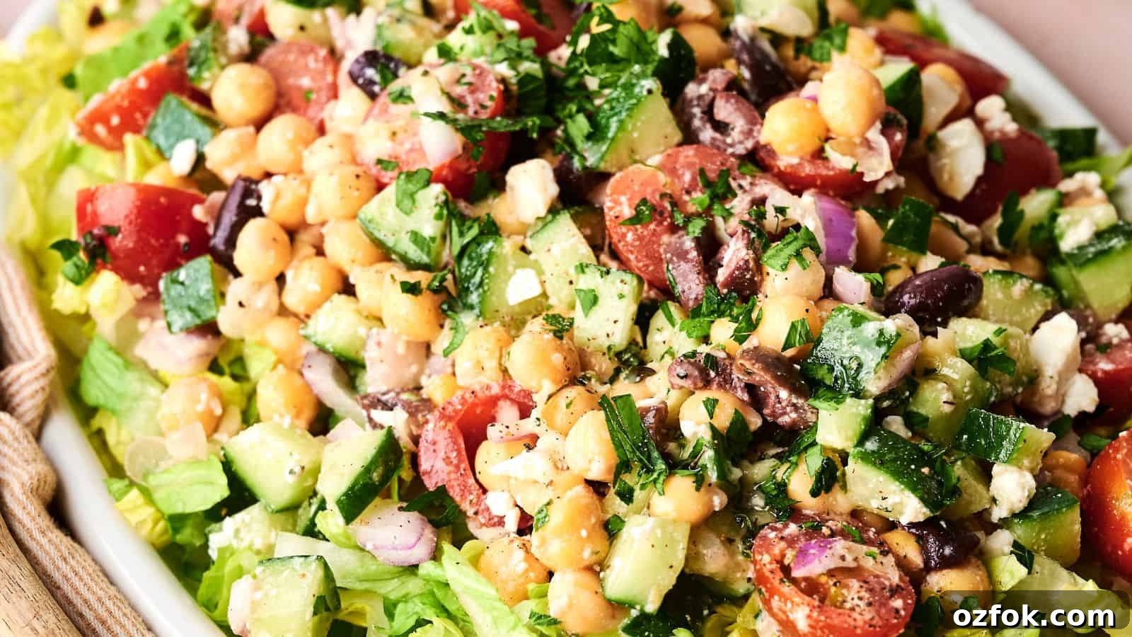 29 Irresistible Salad Recipes Everyone Will Love 28 A fresh salad with chopped cucumbers, cherry tomatoes, chickpeas, red onion, feta cheese, black olives, and parsley on a bed of lettuce.