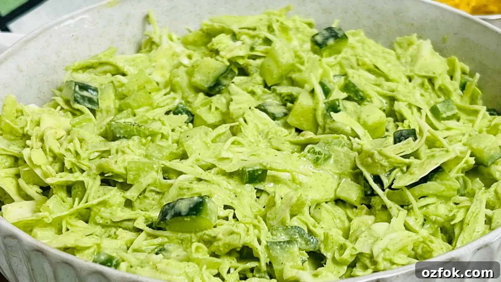 29 Irresistible Salad Recipes Everyone Will Love 5 Cabbage salad in a white bowl with chips in the background.
