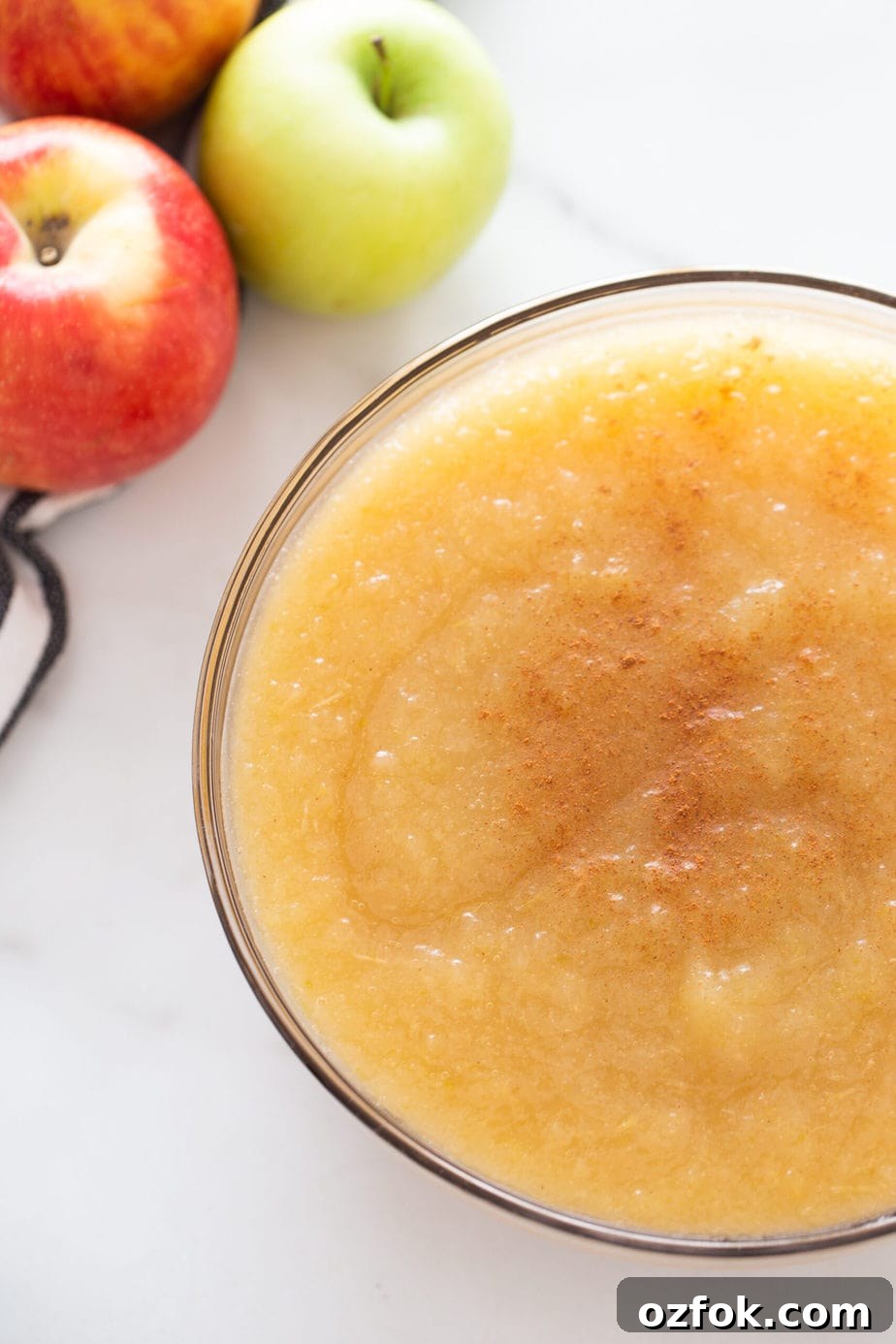 Instant Pot Applesauce Recipe — No-Peel Option Included 4 A clear bowl of applesauce with apples in the upper left hand corner