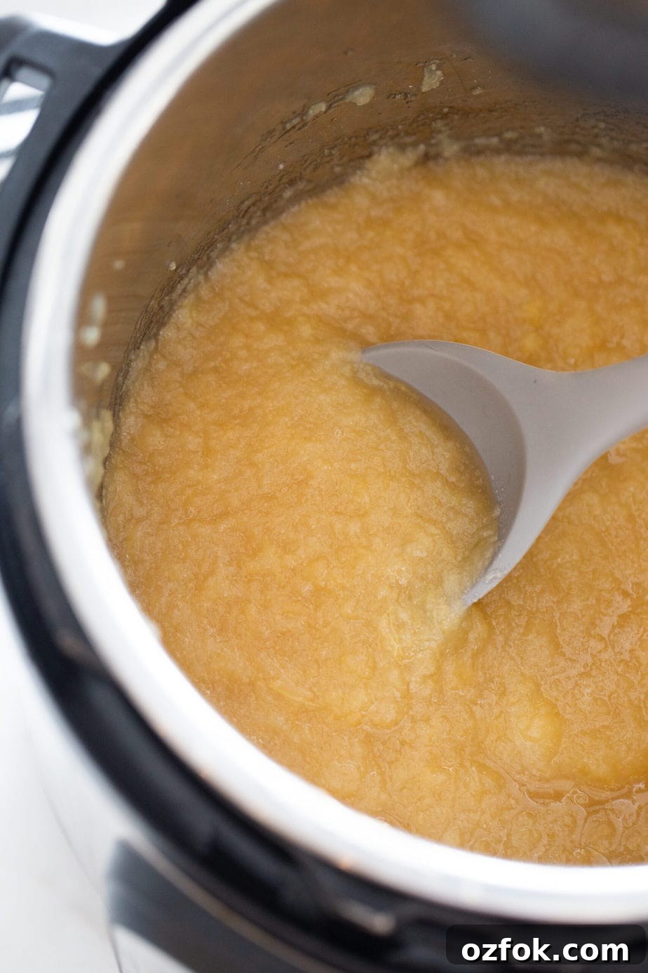 Instant Pot Applesauce Recipe — No-Peel Option Included 7 An instant pot with homemade applesauce and a grey spoon