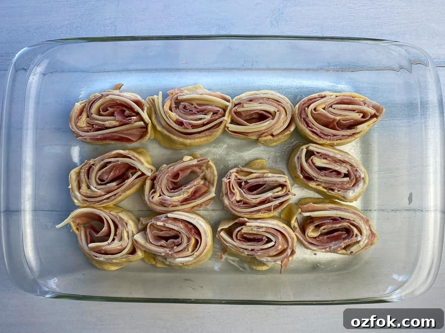 Ham and cheese roll-up slices on their side in a 9 x 13 baking dish