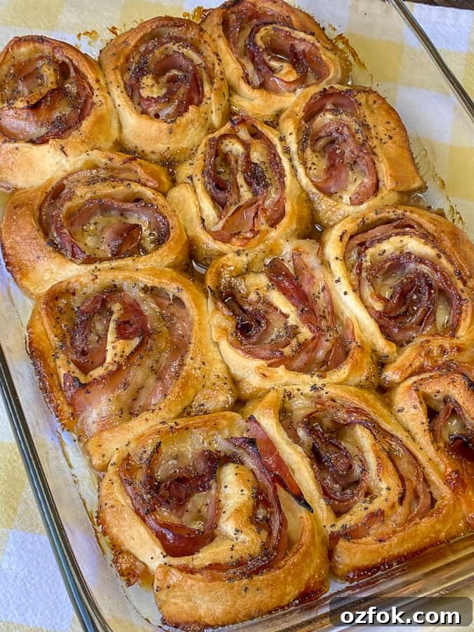 Smaller crescent roll ham roll-ups baked with brown sugar poppyseed topping