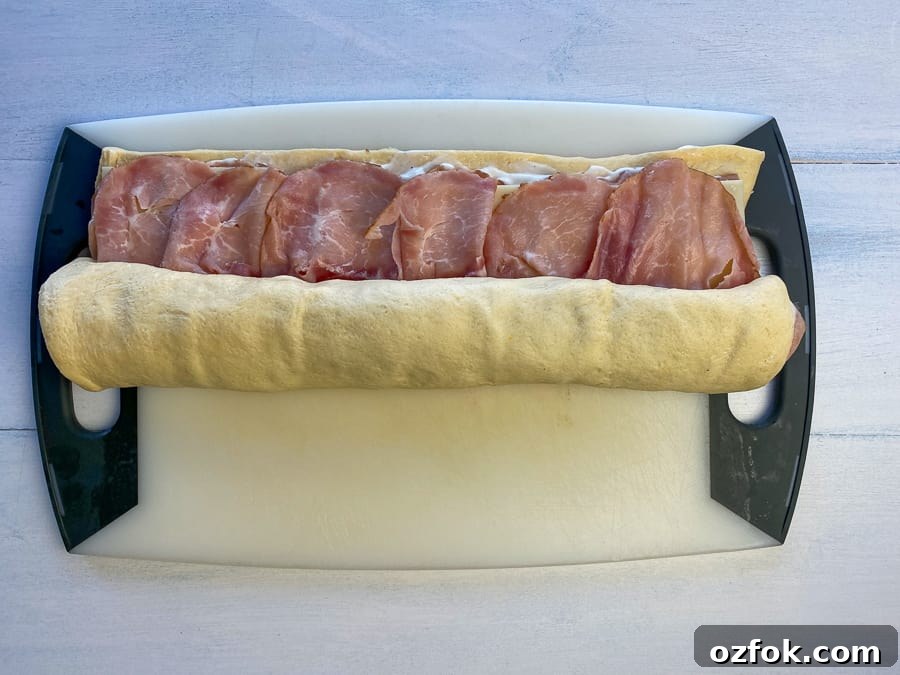 Starting to roll the ham and cheese up in refrigerated dough