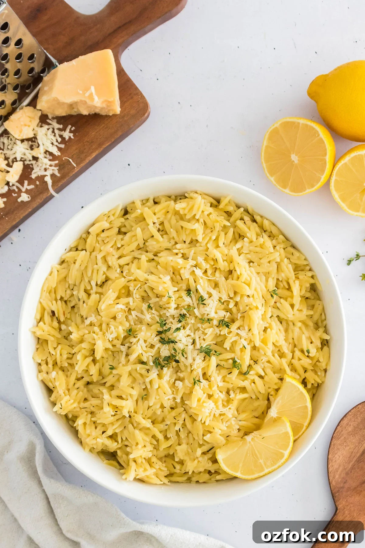 Zesty Lemon Orzo with Parmesan and Fresh Herbs 2 Lemon Orzo in a white bowl with lemon slices.