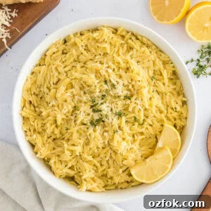 Zesty Lemon Orzo with Parmesan and Fresh Herbs 6 Lemon Orzo served in a white bowl with slices of lemons.