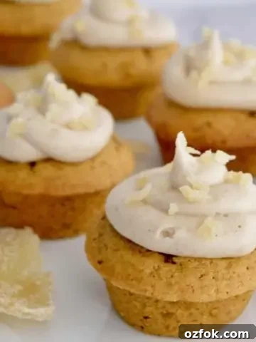 pumpkin ginger cupcakes with cream cheese frosting on a white platter with candied ginger.