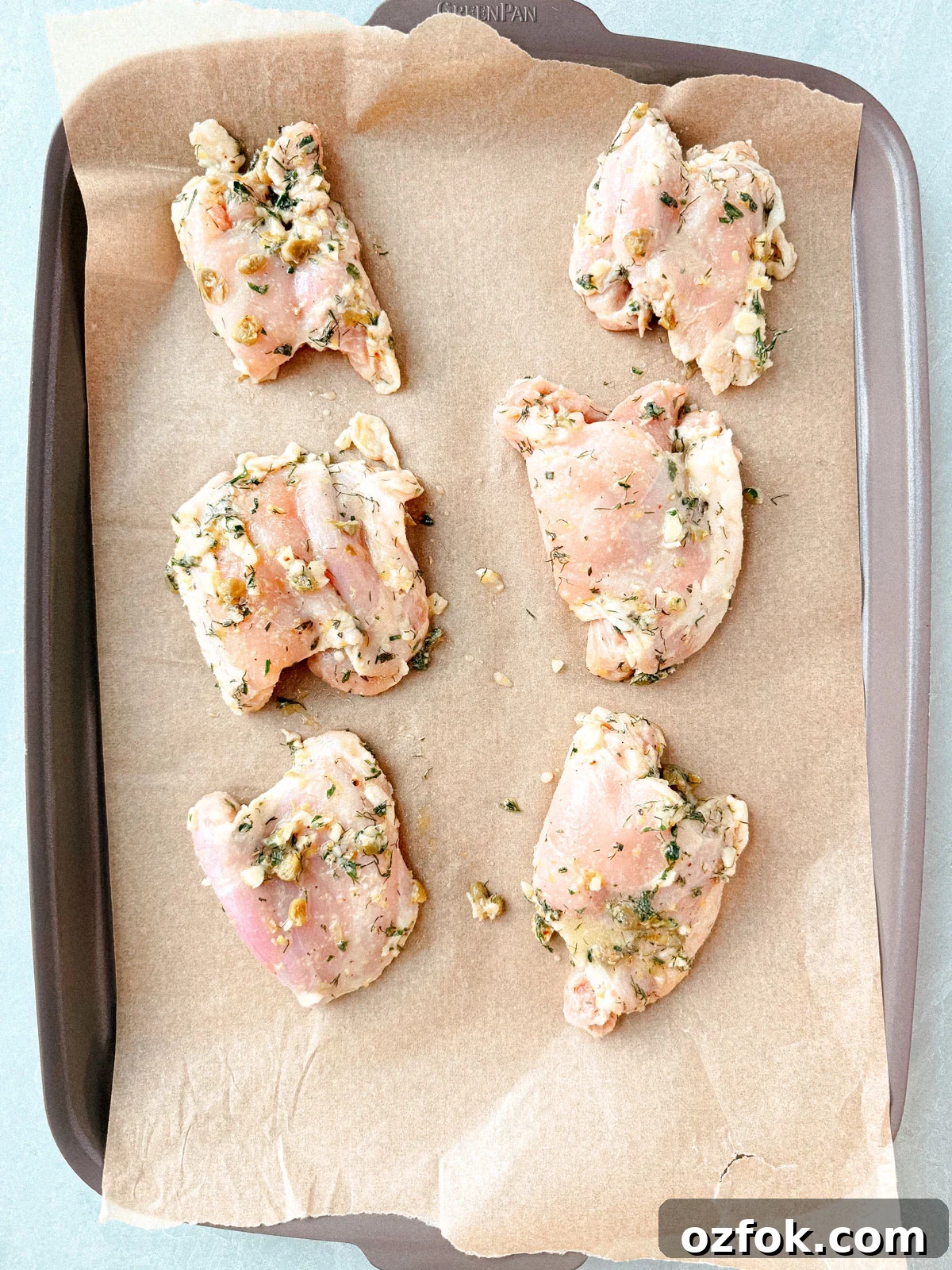 Greek Sheet-Pan Chicken with Tangy Feta and Roasted Veggies 6 Marinated chicken thighs on a sheet pan.