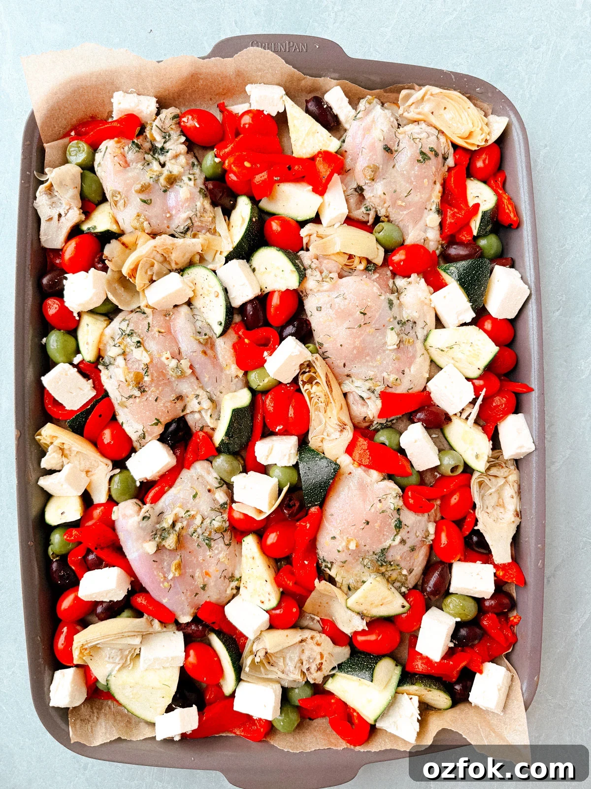 Greek Sheet-Pan Chicken with Tangy Feta and Roasted Veggies 8 Chicken thighs and vegetables spread out on a sheet pan.