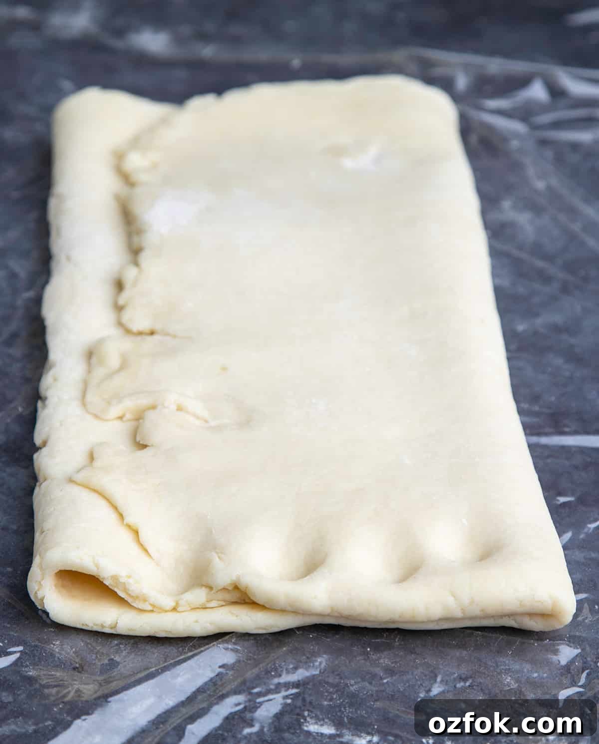 Flaky Gluten-Free Croissants: Buttery Recipe for Perfect Layers 6 Rectangular folded over raw gluten free croissant pastry dough with 4 notches on plastic