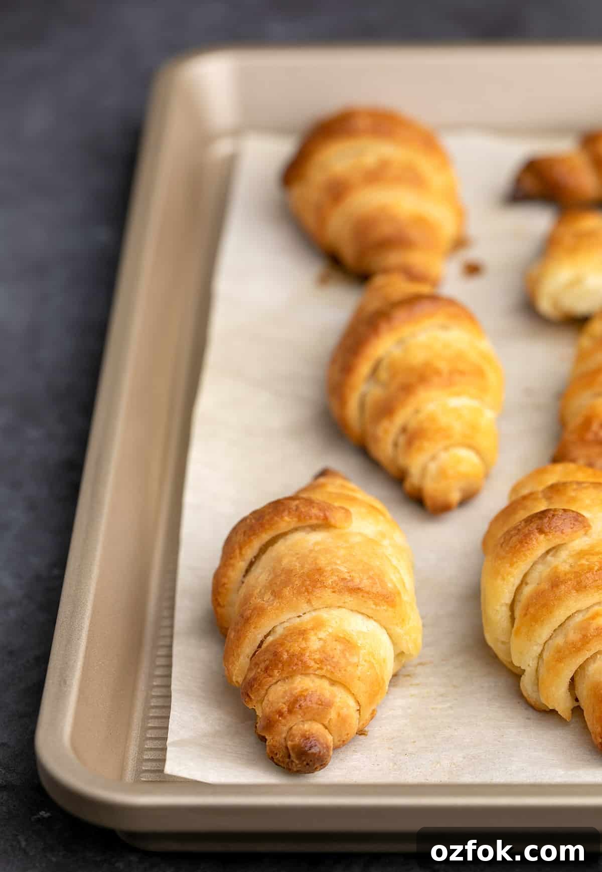 Flaky Gluten-Free Croissants: Buttery Recipe for Perfect Layers 8 Closeup of baked croissants on white paper on tray